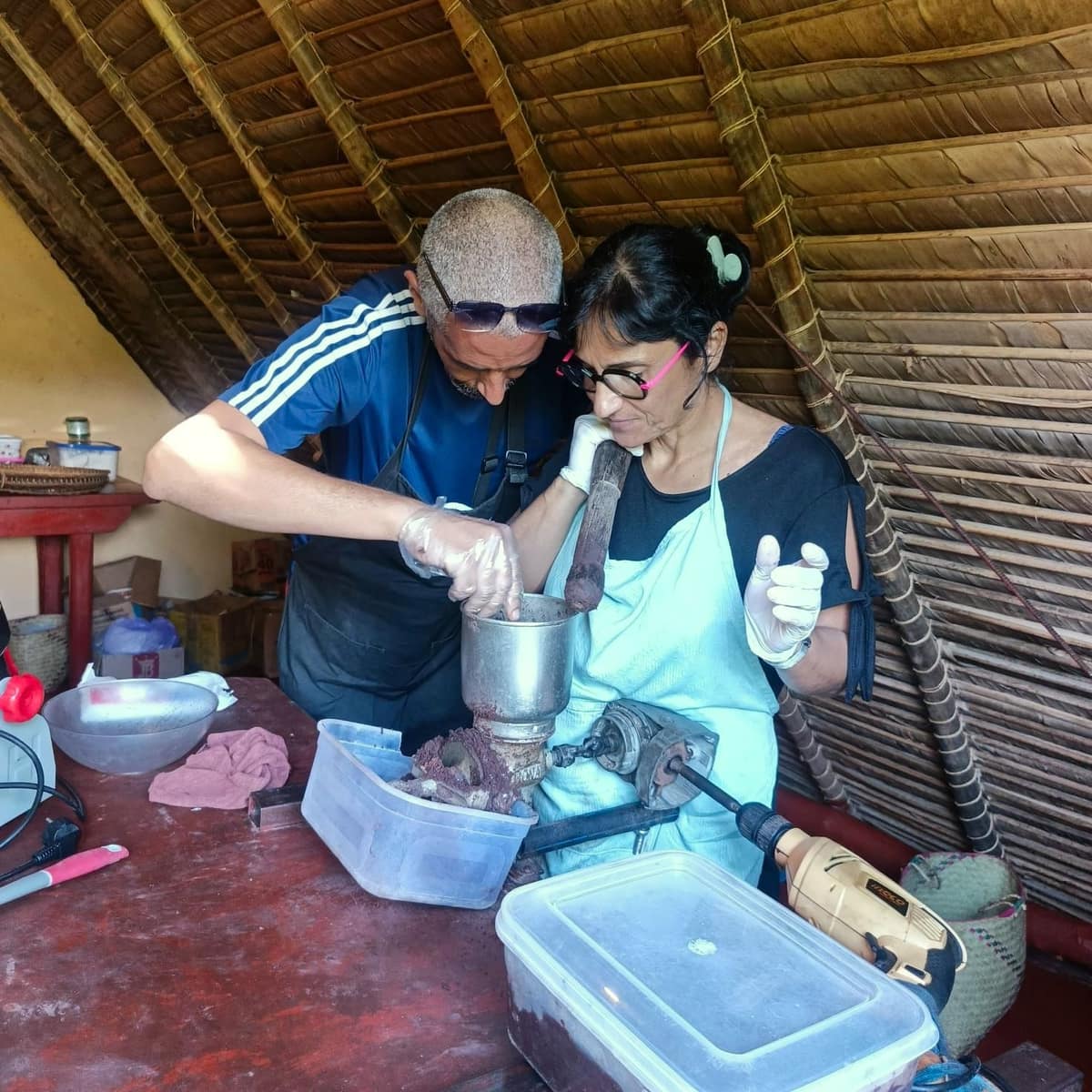 Deux participants passent le cacao au moulin